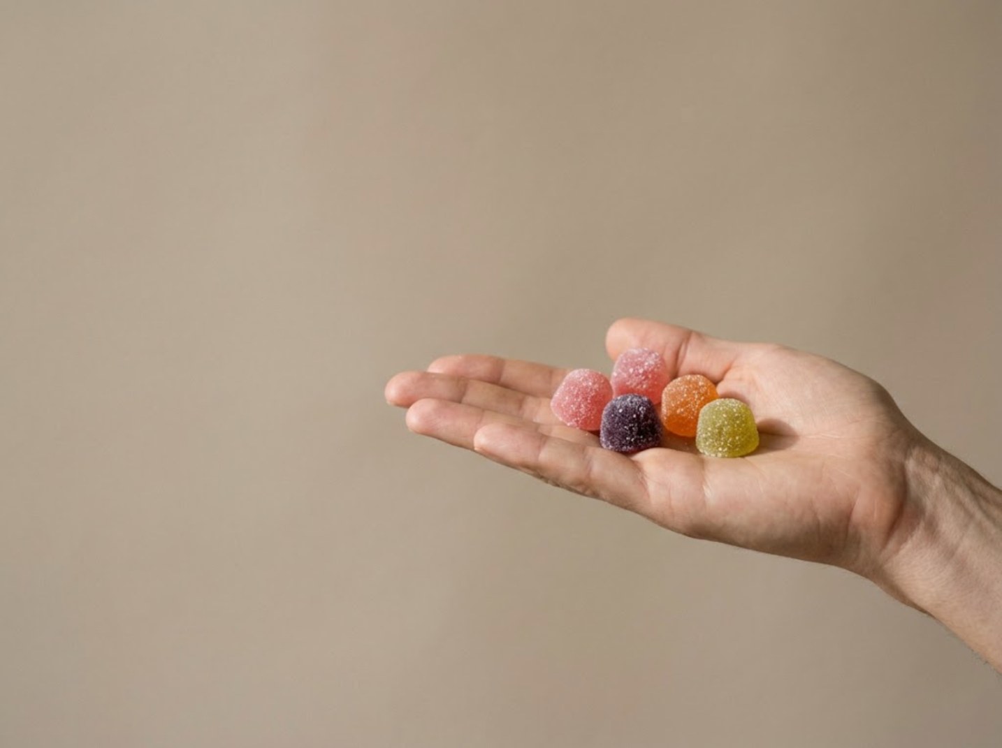 Five sugar-coated creatine gummies in an open palm
